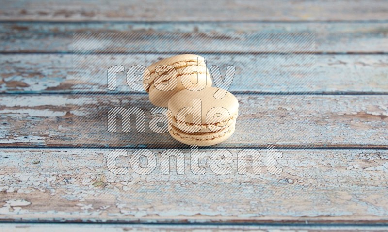 45º Shot of two White Caramel fleur de sel macarons on a light blue wooden background