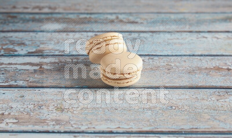 45º Shot of two White Caramel fleur de sel macarons on a light blue wooden background