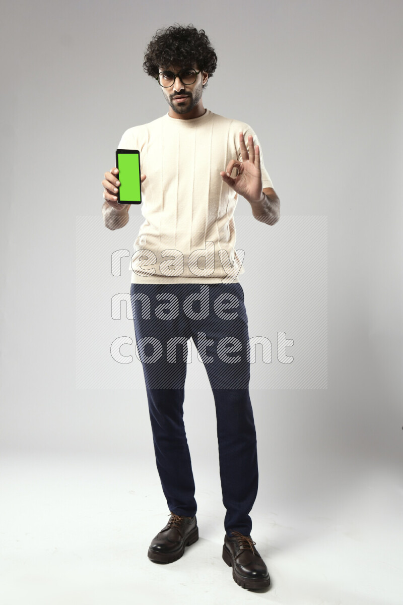 A man wearing casual standing and showing a phone screen on white background