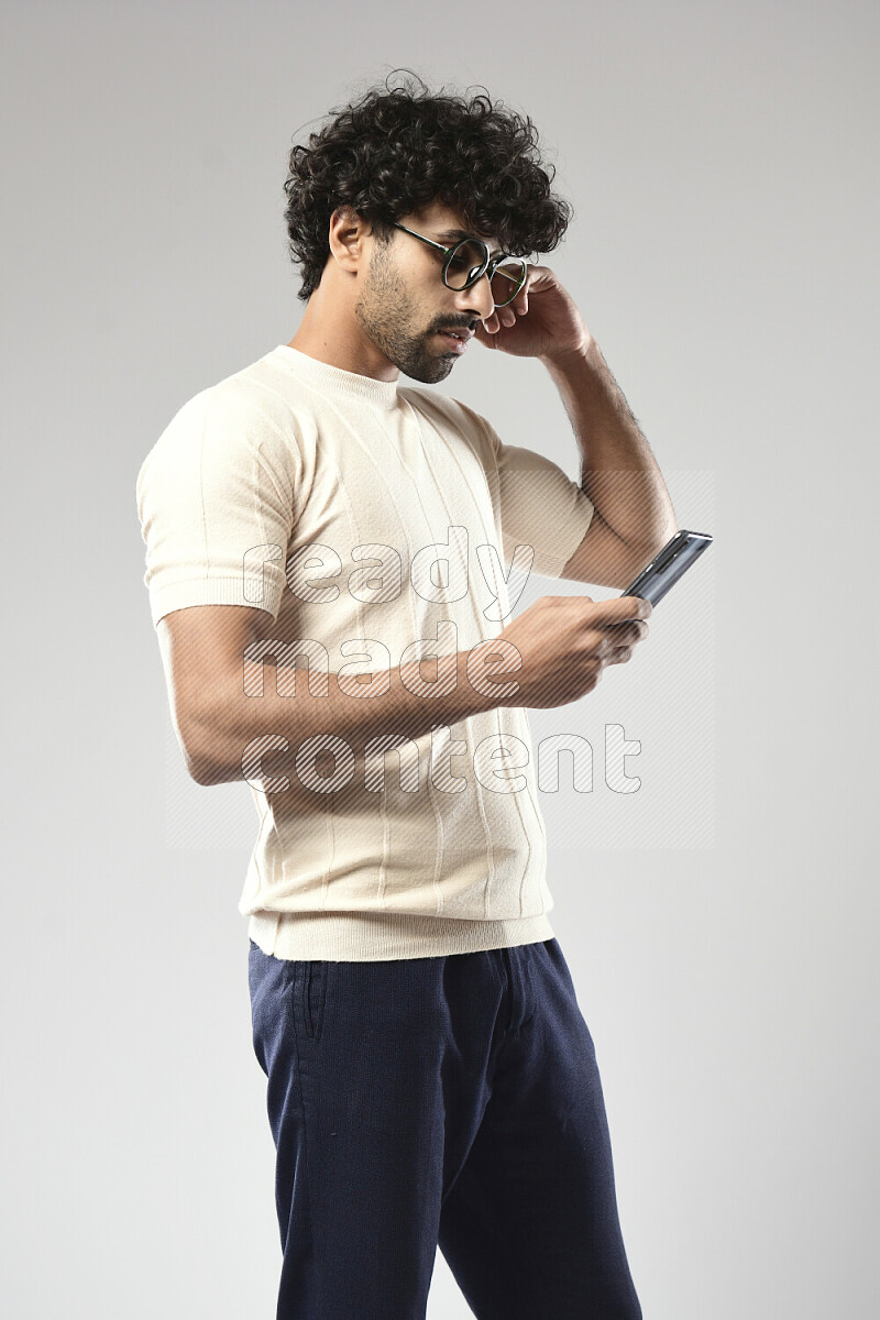 رجل يرتدي ملابس كاجوال يتصفح الهاتف علي خلفية بيضاء
