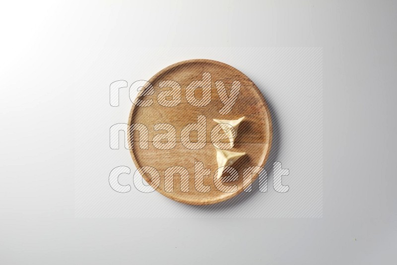 Two Sambosas on a wooden round plate on a white background