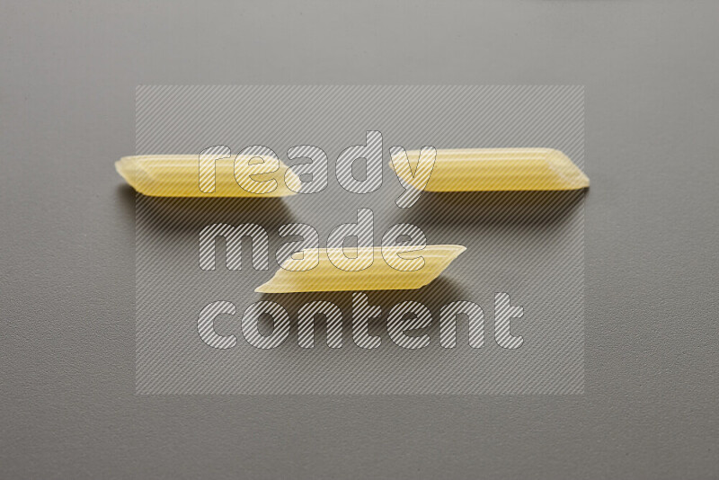 Mini penne pasta on grey background