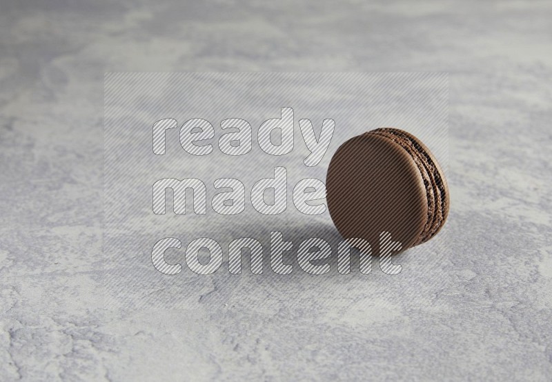 45º Shot of Brown Dark Chocolate macaron on white  marble background
