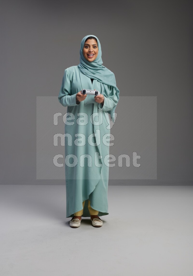 Saudi Woman wearing Abaya standing Playing Games on Gray background