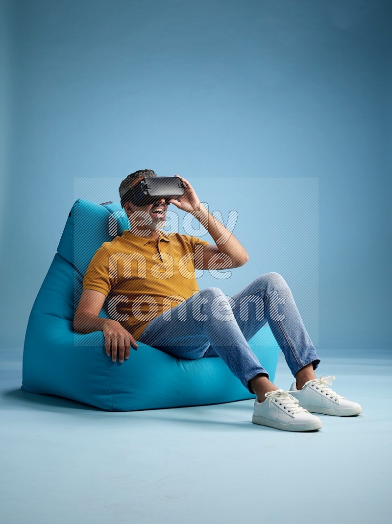 A man sitting on a blue beanbag and gaming with VR