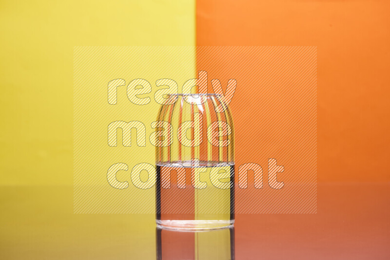 The image features a clear glassware filled with water, set against yellow and orange background