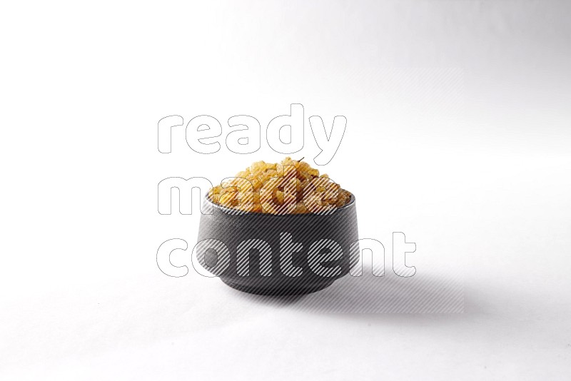 Raisins in a black pottery bowl on white background