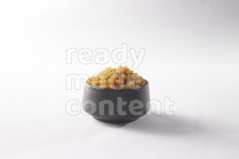 Raisins in a black pottery bowl on white background