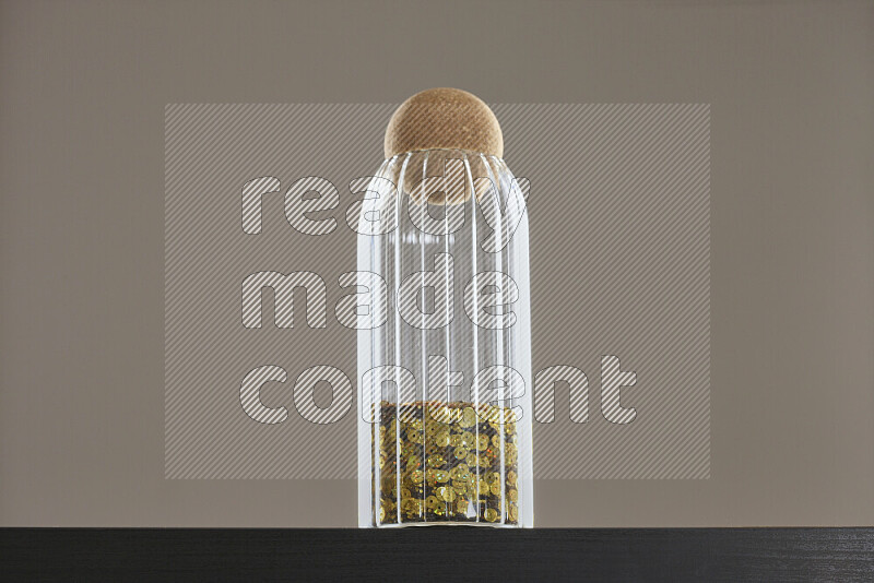 Sequins in a glass jar on black background