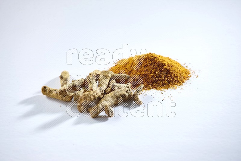 Turmeric powder and dried turmeric whole fingers on white flooring