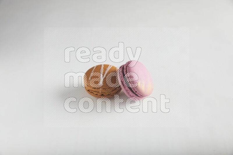 45º Shot of of two assorted Brown Irish Cream, and Purple Strawberry macarons on white background