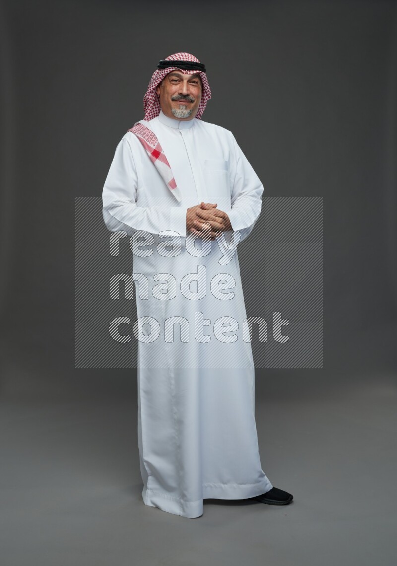 Saudi man with shomag Standing Interacting with the camera on gray background