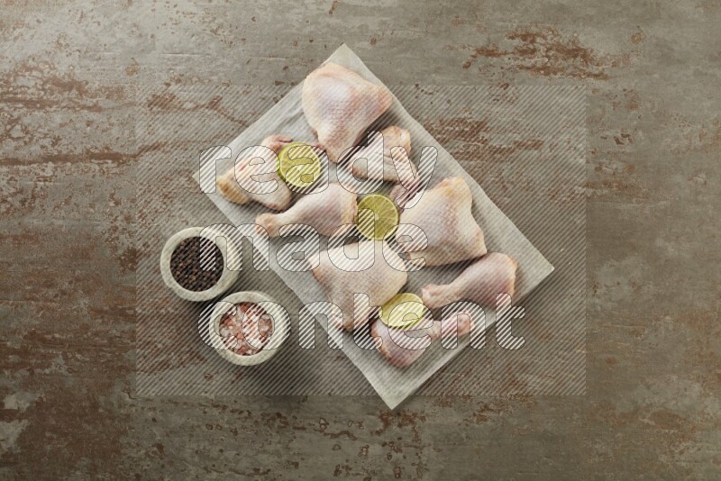 Mixed fresh chicken pieces on a parchment paper direct on a textured rustic background
