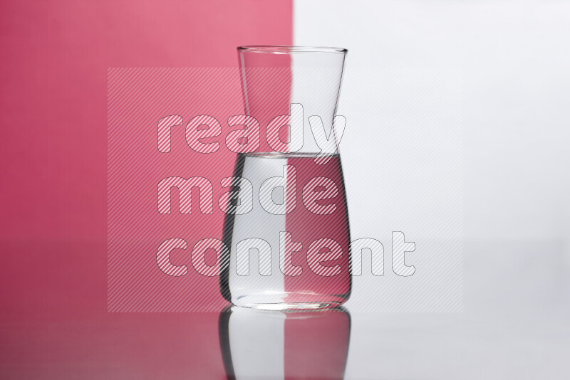 The image features a clear glassware filled with water, set against white and pink background