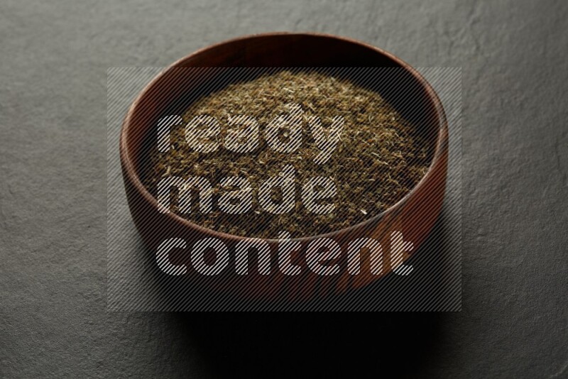 wooden round sauce bowl filled with herbs on grey textured countertop
