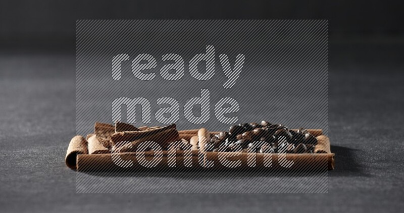 مربعان من أعواد القرفة ممتلئان بحبوب القهوة وقطع من القرفة علي خلفية سوداء