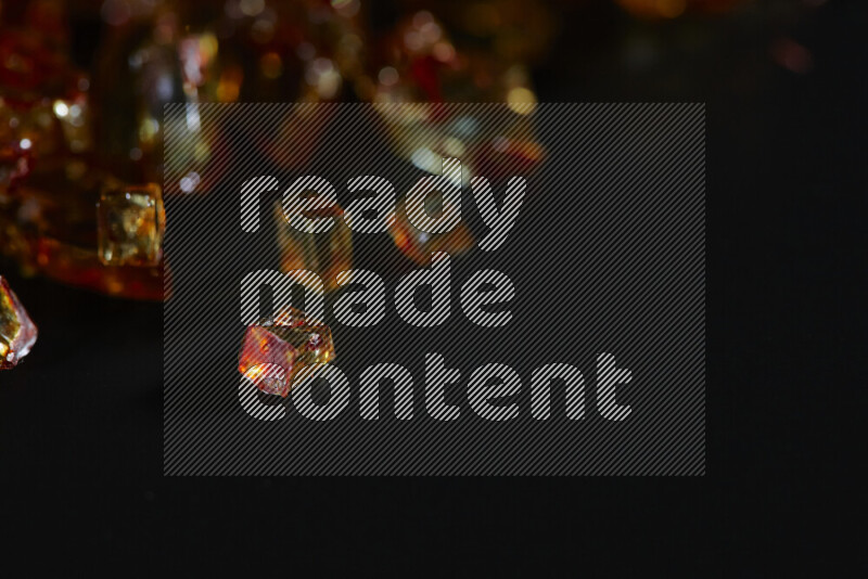 Transparent orange fragments of glass scattered on a black background