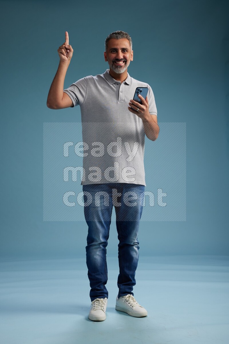 Man Standing texting on phone on blue background