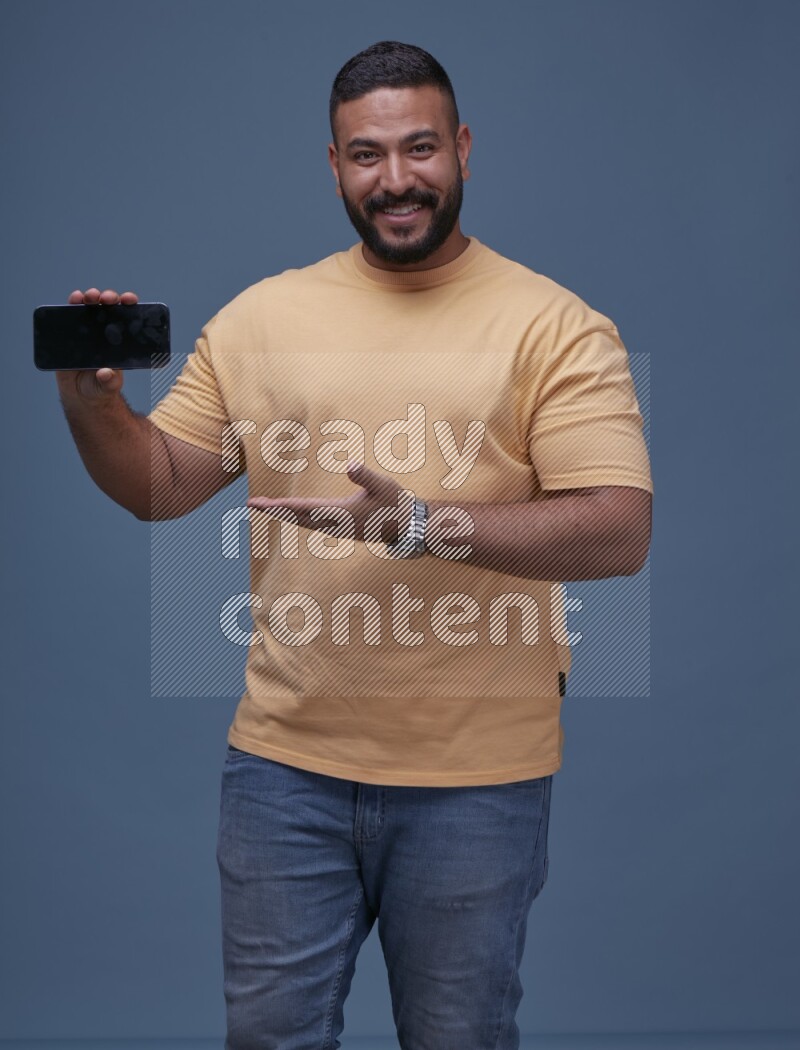 A man Showing His Smart Phone on Blue Background wearing Orange T-shirt