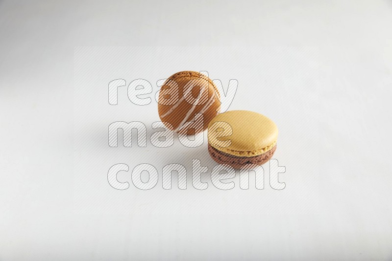 45º Shot of of two assorted Brown Irish Cream, and Yellow, and Brown Chai Latte macarons on white background