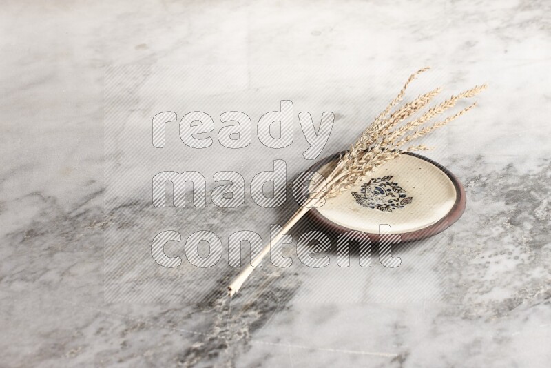 Wheat stalks on decorative pottery plate on grey marble background