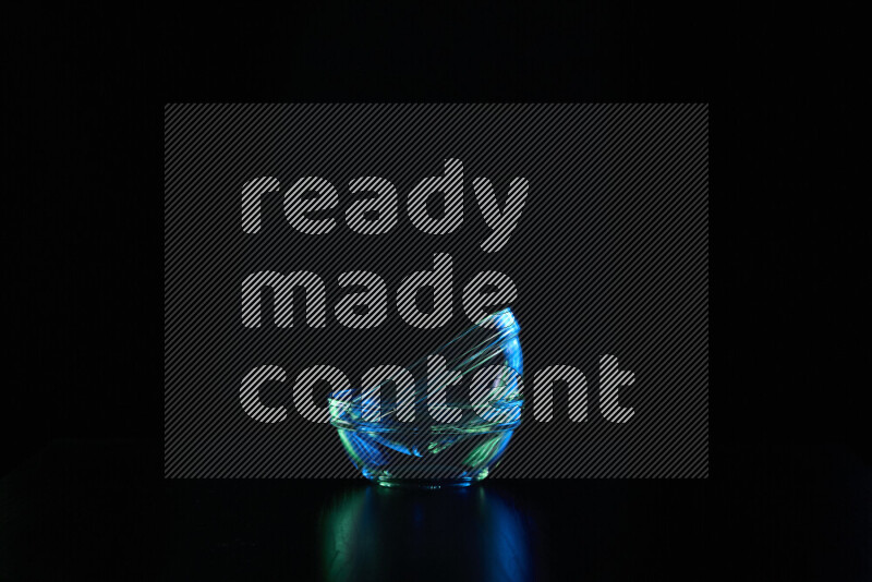 Glassware with rim light in blue and green against black background