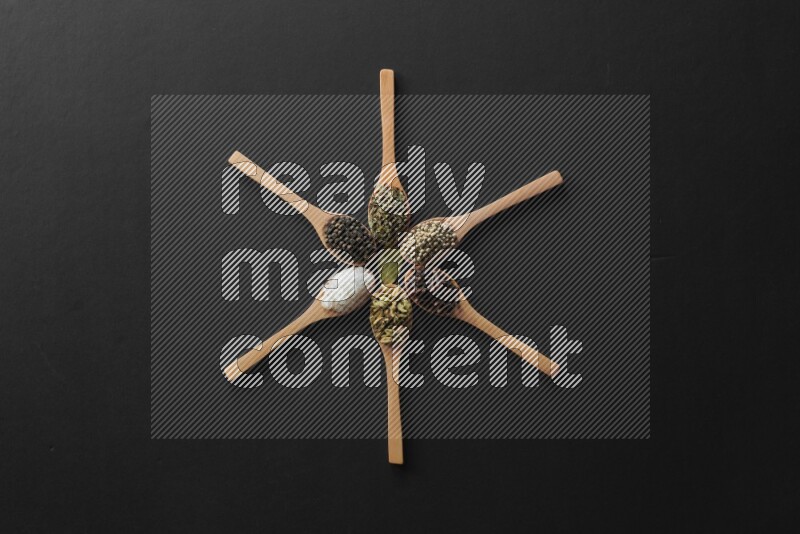 الفلفل الأبيض والقرنفل والهيل والملح والفلفل الأسود والريحان المجفف في معالق خشبية علي شكل ساعة علي خلفية سوداء