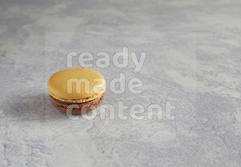 45º Shot of Yellow and Brown Chai Latte macaron on white  marble background