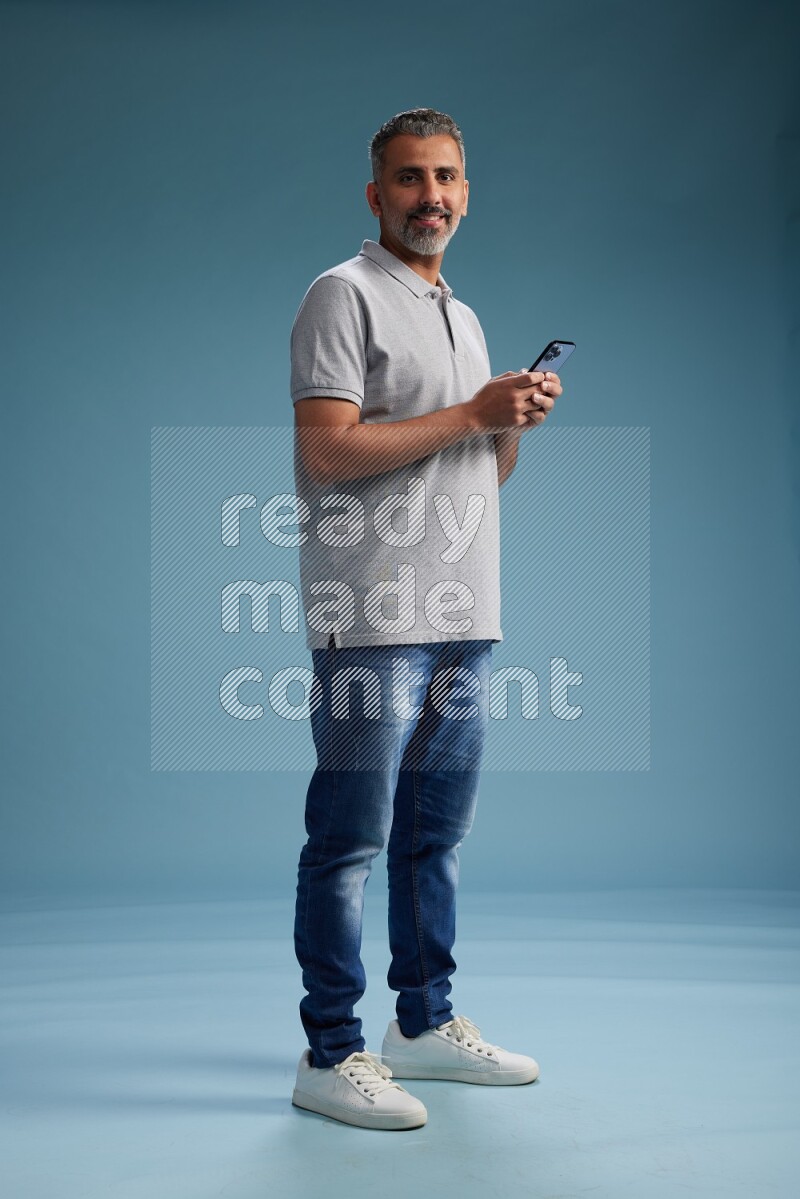 Man Standing texting on phone on blue background