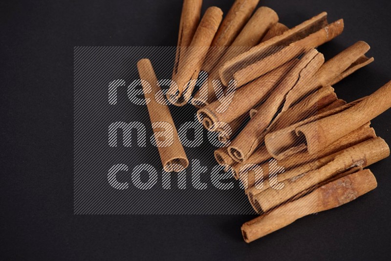 Cinnamon sticks stacked on black flooring