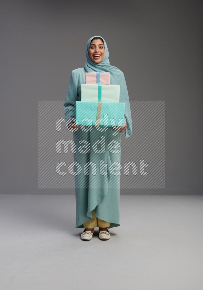 Saudi Woman wearing Abaya standing holding gift box on Gray background