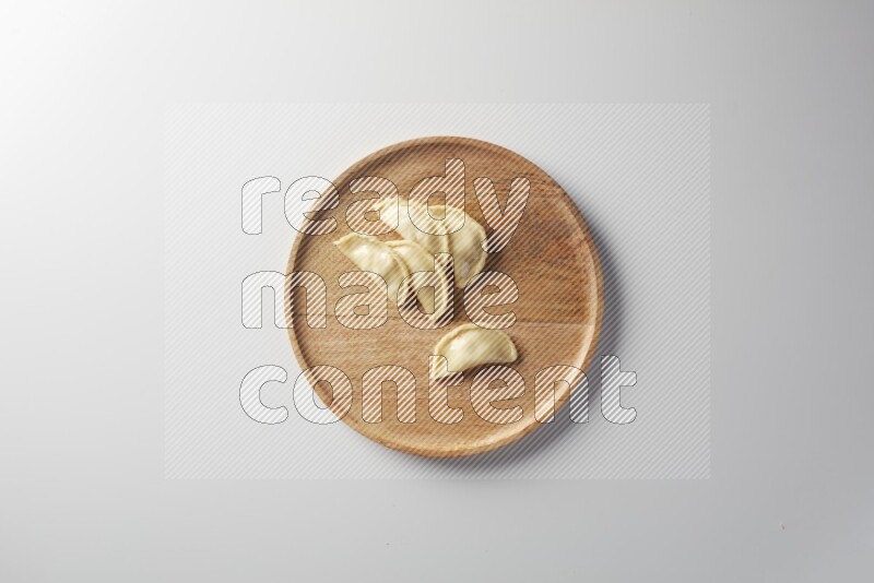 Five Sambosas on a wooden round plate on a white background