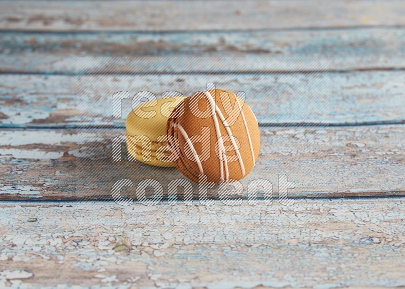 45º Shot of of two assorted Brown Irish Cream, and Yellow Vanilla macarons on light blue background