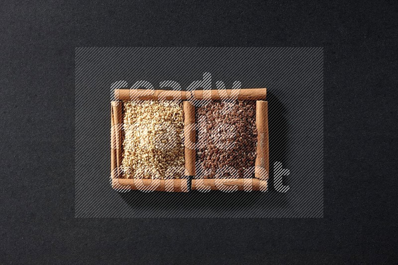 2 squares of cinnamon sticks full of flaxseeds and sesame on black flooring