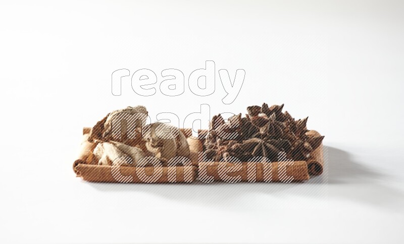 مربعان من أعواد القرفة ممتلئان باليانسون النجمي والزنجبيل المجفف علي خلفية بيضاء