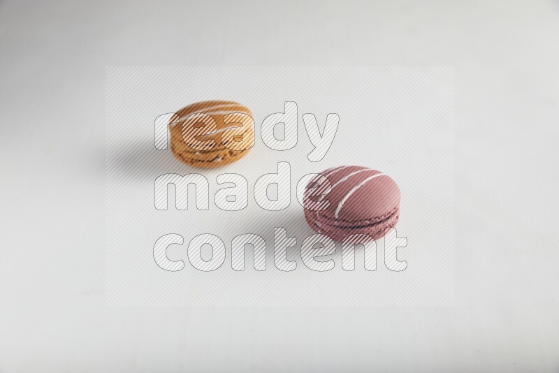 45º Shot of of two assorted Brown Irish Cream, and Red Poppy Flower macarons on white background