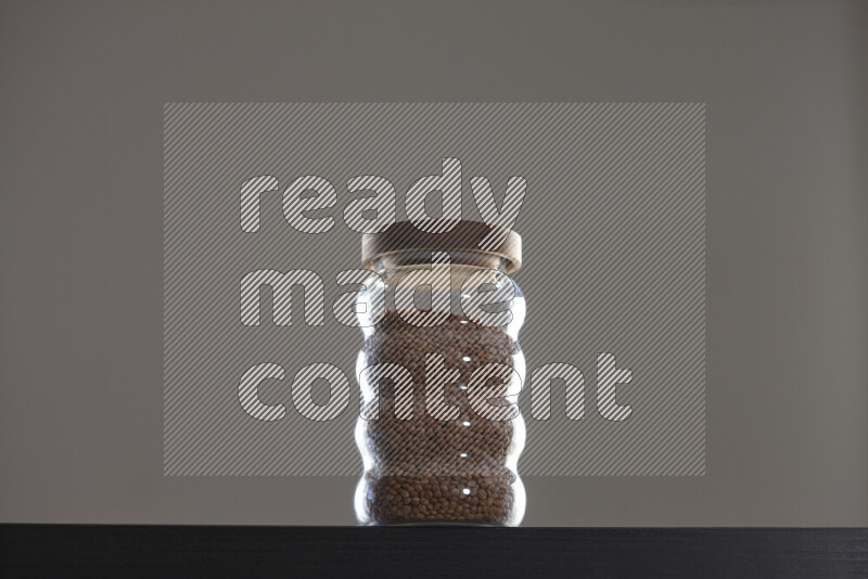 Brown lentils in a glass jar on black background
