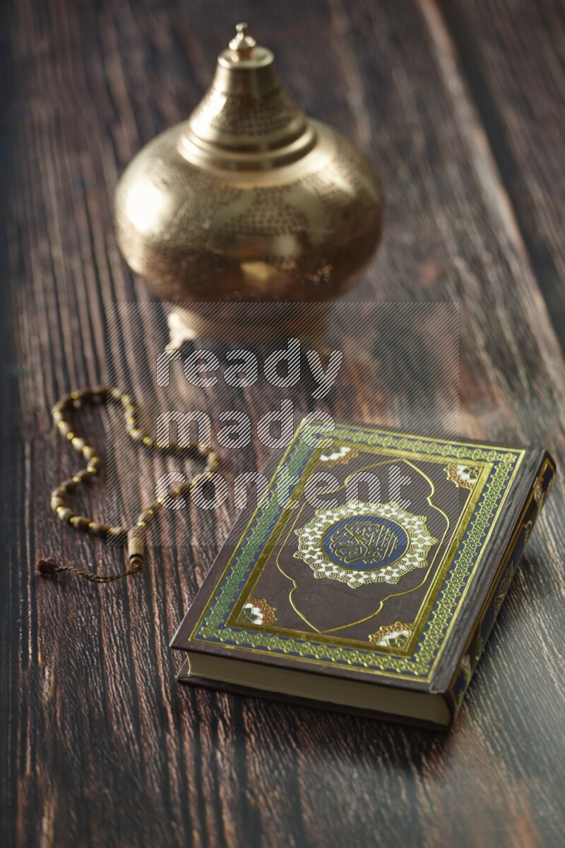A golden lantern with different drinks, dates, nuts, prayer beads and quran on brown wooden background
