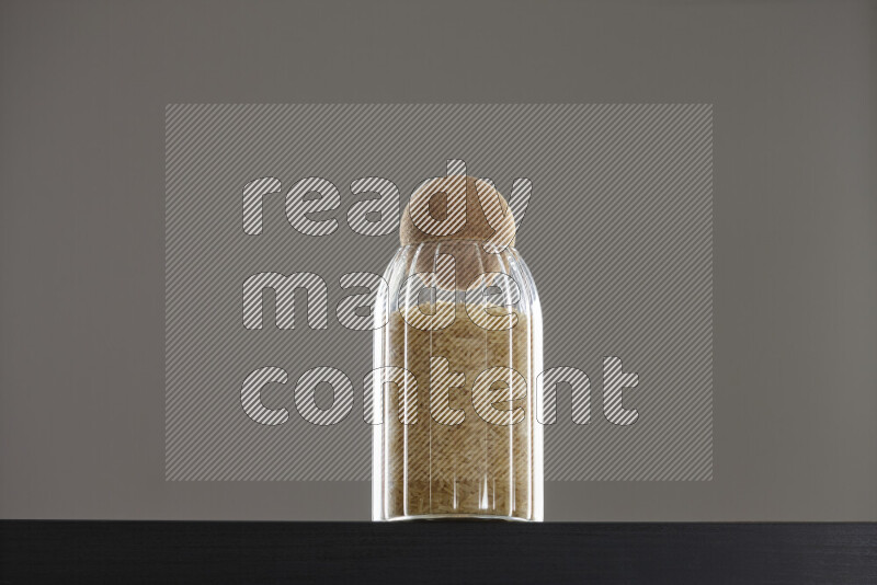 Basmati golden rice in a glass jar on black background