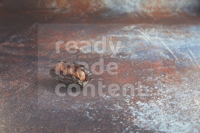 one hazelnut stuffed madjoul date on a rustic reddish background