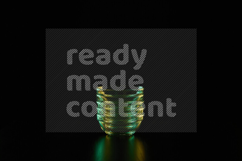 Glassware with rim light in green and yellow against black background