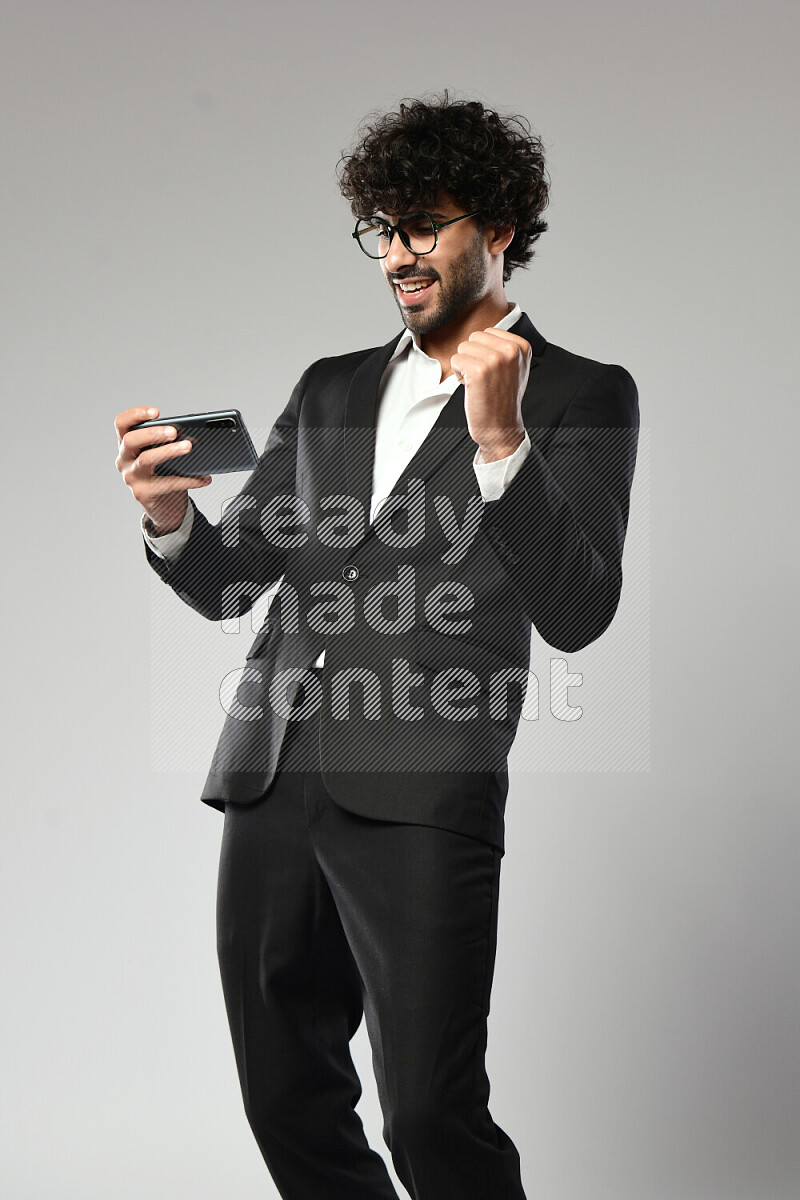 A man wearing formal standing and gaming on the phone on white background