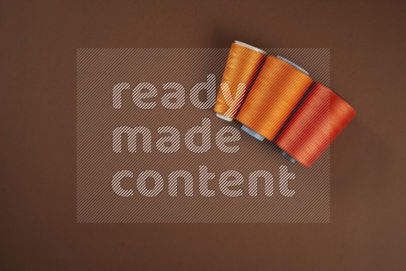 An orange collection of sewing and tailoring tools arranged on a brown background