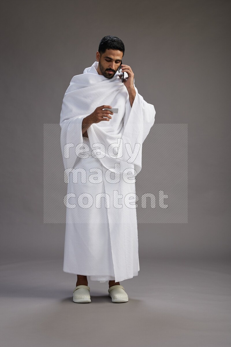 A man wearing Ehram Standing holding ATM card on gray background