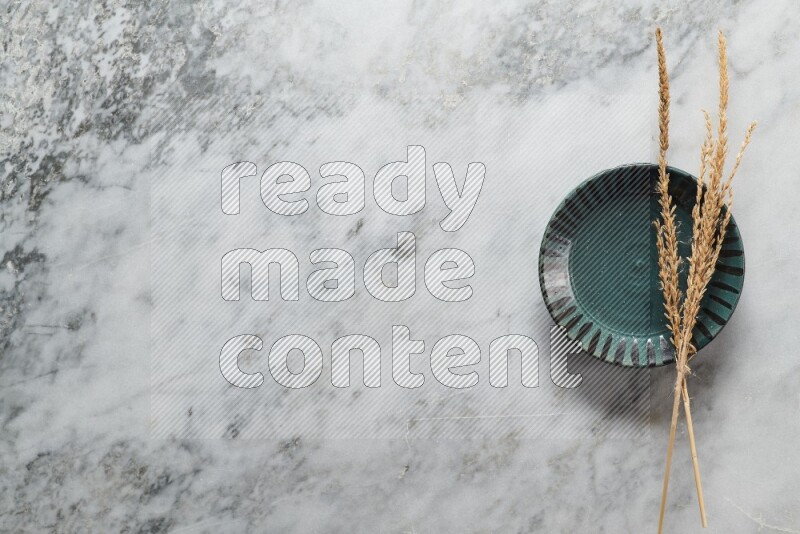 Wheat stalks on multicolored pottery plate on grey marble background