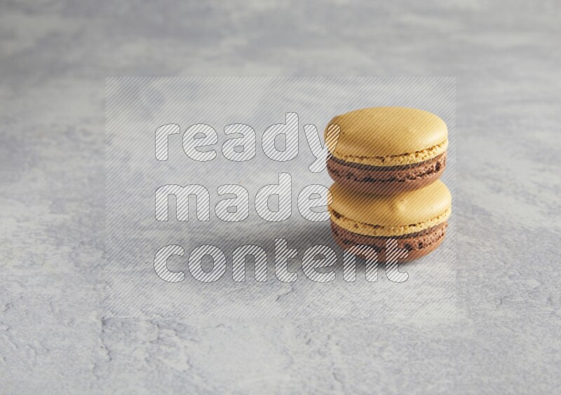 45º Shot of two Yellow and Brown Chai Latte macarons r on white  marble background