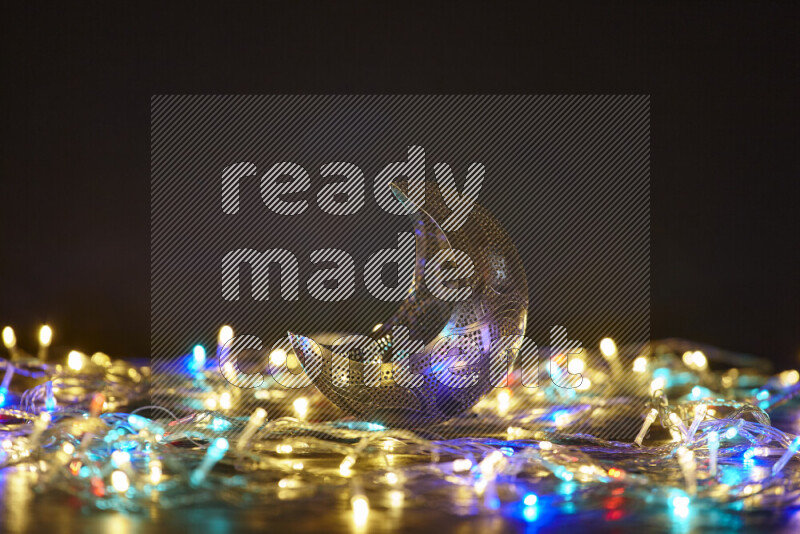 A traditional ramadan lantern surrounded by glowing fairy lights in a dark setup