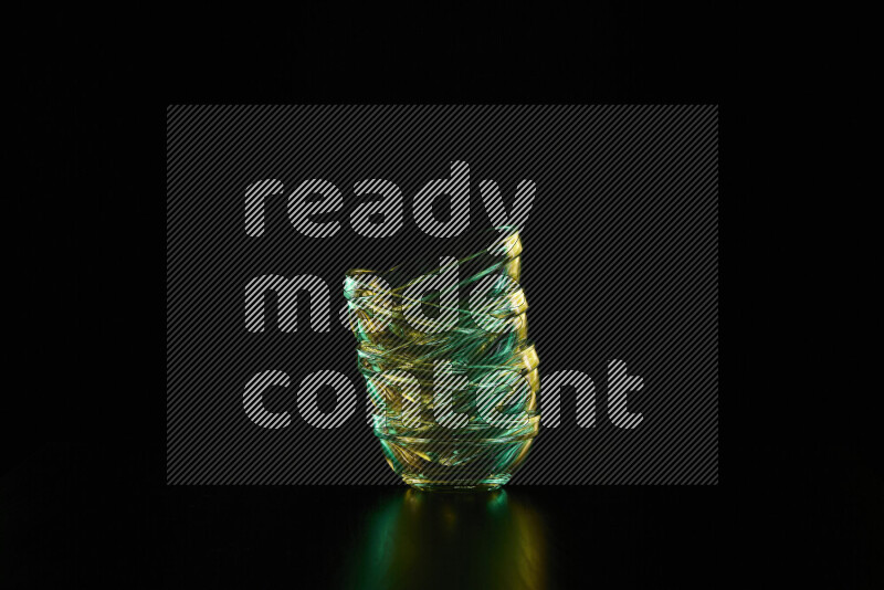 Glassware with rim light in green and yellow against black background