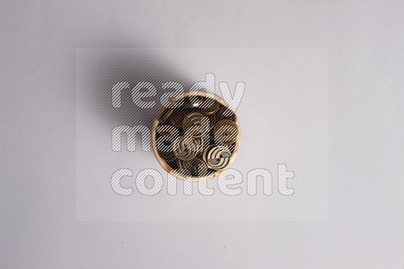 A beige pottery bowl full of colored buttons on grey background
