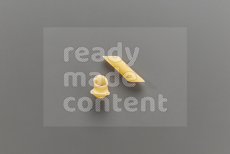 Pipe pasta with other types of pasta on grey background